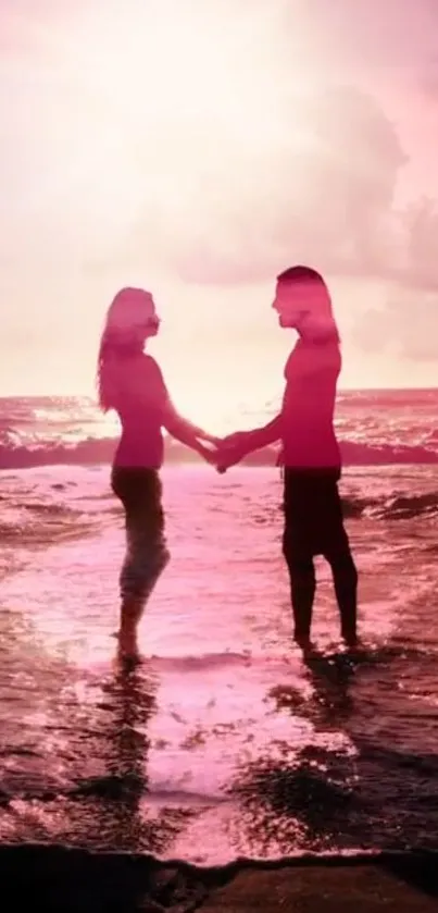 Couple at sunset on a beach with a pink sky.