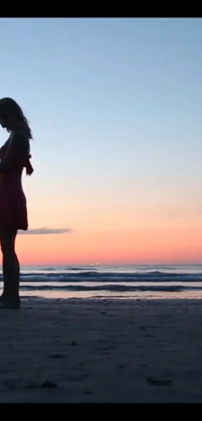 Couple's silhouette on beach at sunset with colorful sky.