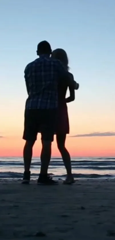 Silhouette couple embracing on a beach at sunset with ocean in background.