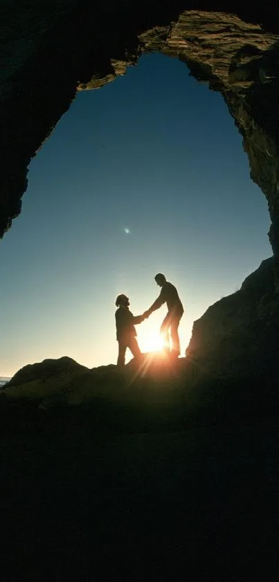 Silhouette of couple at sunset under a natural rock arch by the beach.