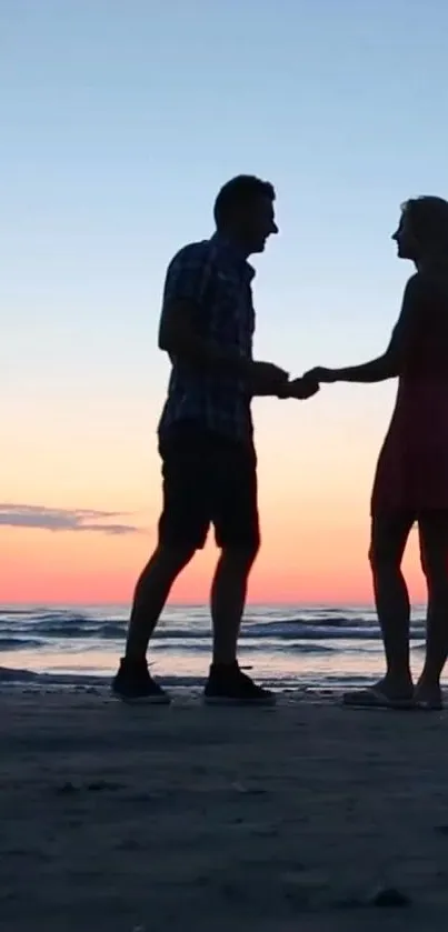 A couple's silhouette on the beach at sunset.