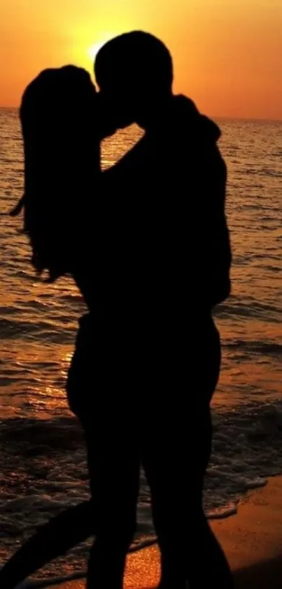 Silhouette of a couple kissing at sunset on the beach.