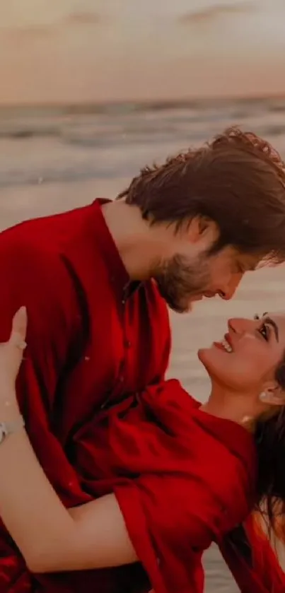 Romantic couple embracing at beach during sunset with red attire.