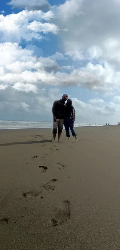 Couple walking on a serene beach under a cloudy sky.