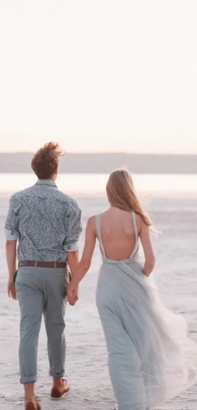 Couple holding hands on serene beach at sunset.