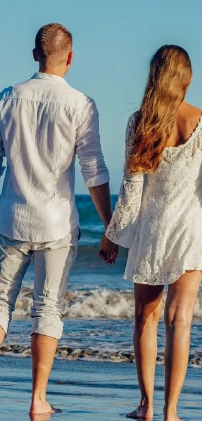 Couple walking on beach holding hands in sunlight.