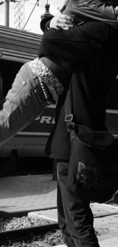 Black and white photo of a couple embracing at a train station.