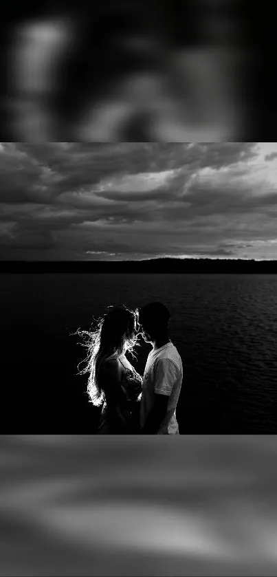 Romantic black and white couple silhouette at sunset over water.