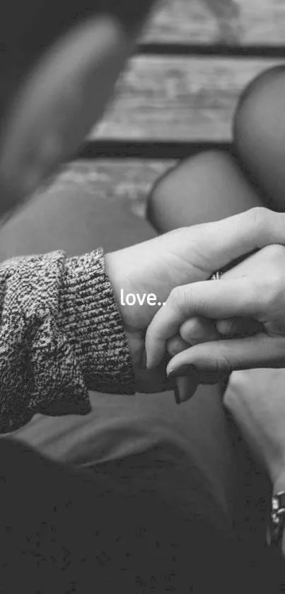 Black and white wallpaper of hands holding, with the word 'love' centered.