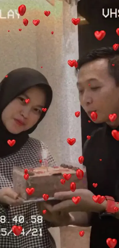 Couple shares cake with red hearts floating around in celebration.