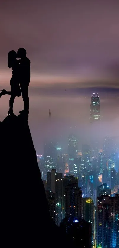 Silhouetted couple on mountain overlooking vibrant cityscape at night.