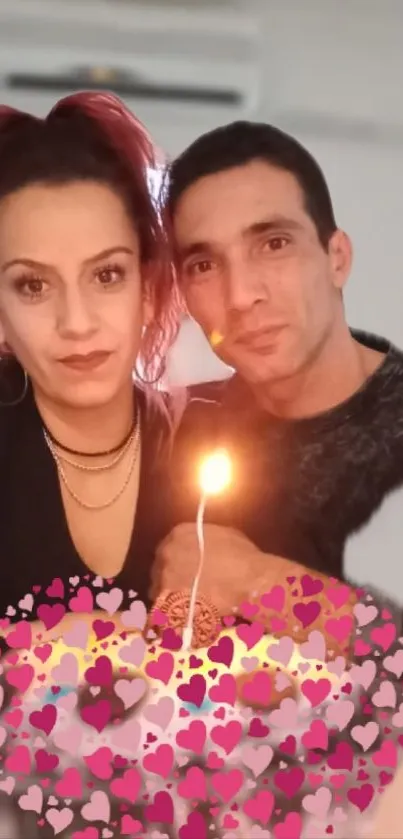 A couple enjoying a romantic candlelit moment with heart decorations.