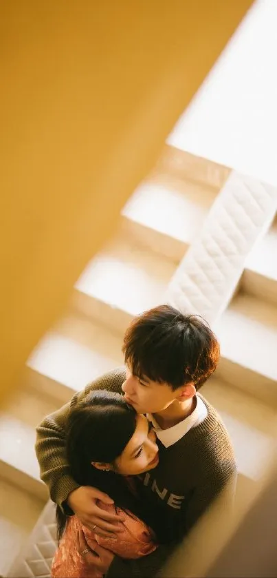 Couple sharing a warm embrace on a staircase in soft lighting.