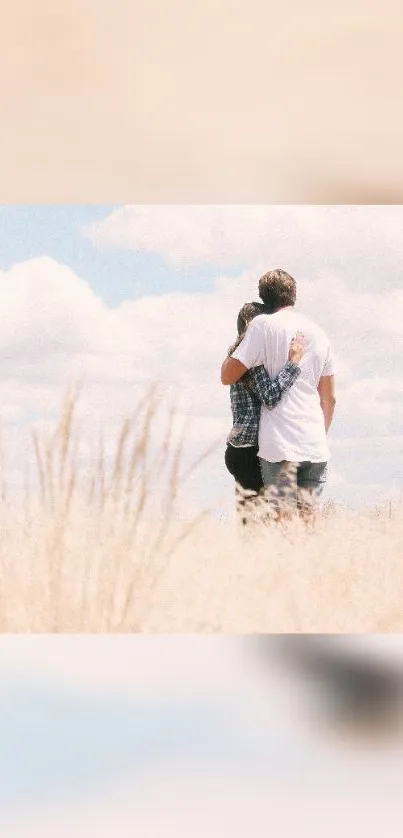 Couple embracing in a serene grassy field with clouds.