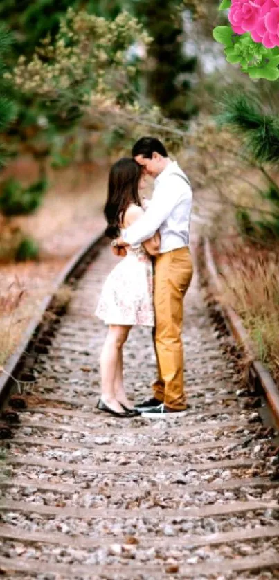 Romantic couple embraces on railway tracks with lush green surroundings.