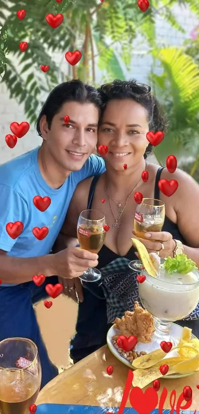 Romantic couple with drinks and red hearts in outdoor setting.