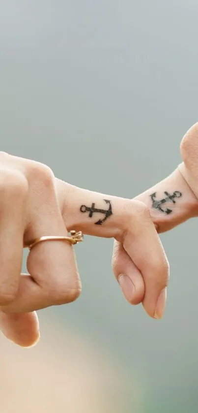 Two hands with tattoos gently intertwined in a romantic gesture.