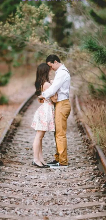 Couple embracing on a railway surrounded by nature.