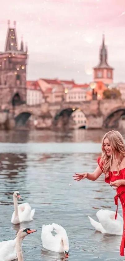 Woman in red by a river with swans and bridge at sunset.