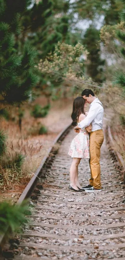 A couple shares a romantic kiss on a forest railway, surrounded by greenery.