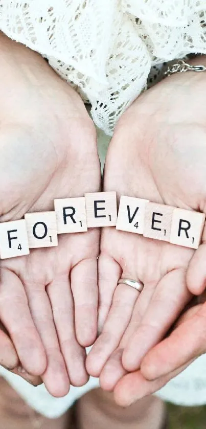 Hands holding Scrabble tiles spelling 'FOREVER' on grass.