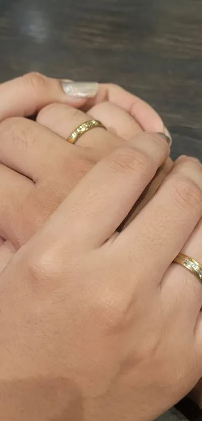 Couple holding hands with gold rings, conveying love.