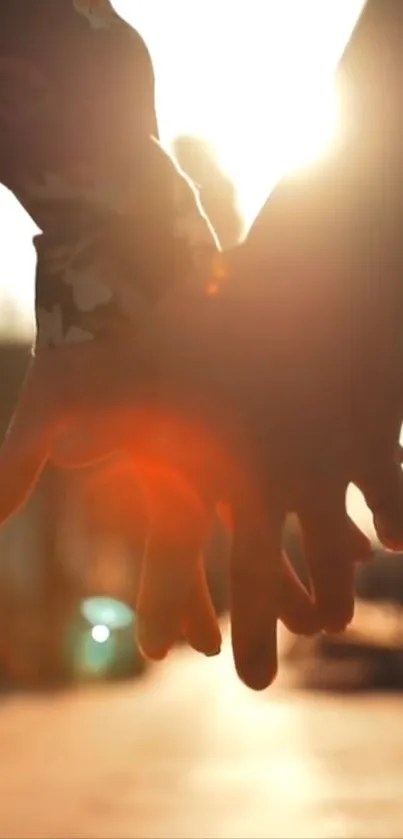Two hands holding at sunset, creating a silhouette effect.