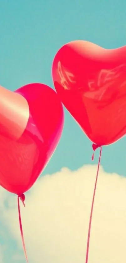 Two red heart-shaped balloons in a clear blue sky.