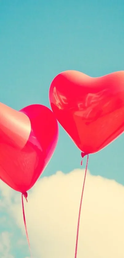 Two red heart-shaped balloons float in a clear blue sky.