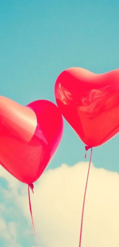 Two red heart-shaped balloons floating in a bright blue sky.