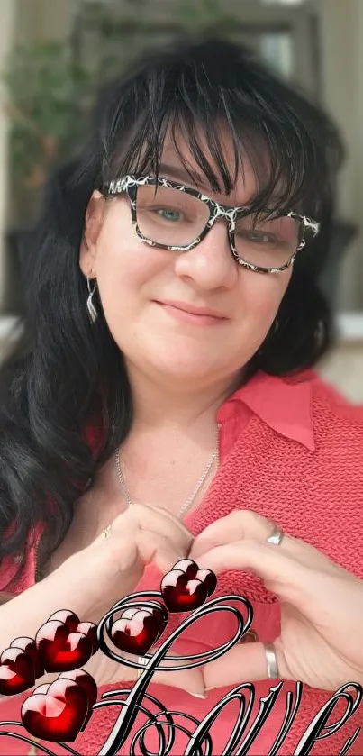 Woman with glasses forming a heart with hands.