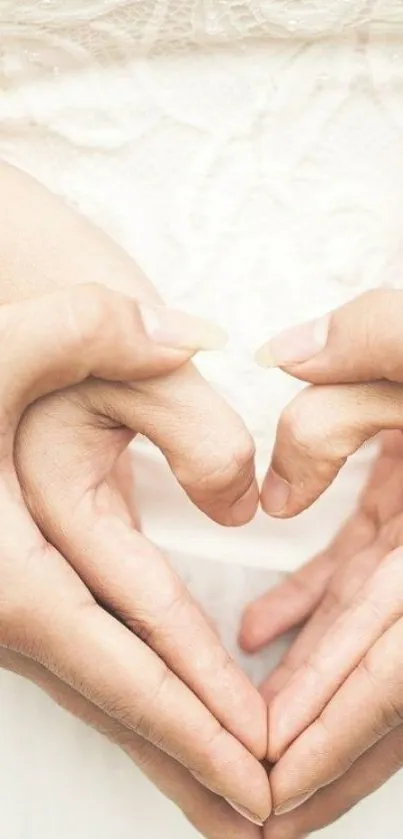 Intertwined hands forming a heart against a cream background.