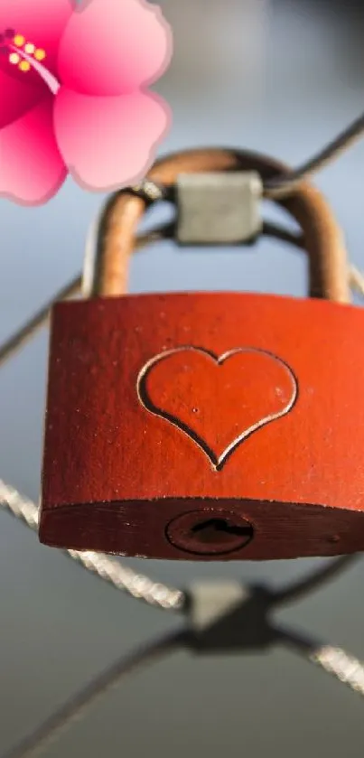 Red heart lock with pink flower on metal fence.