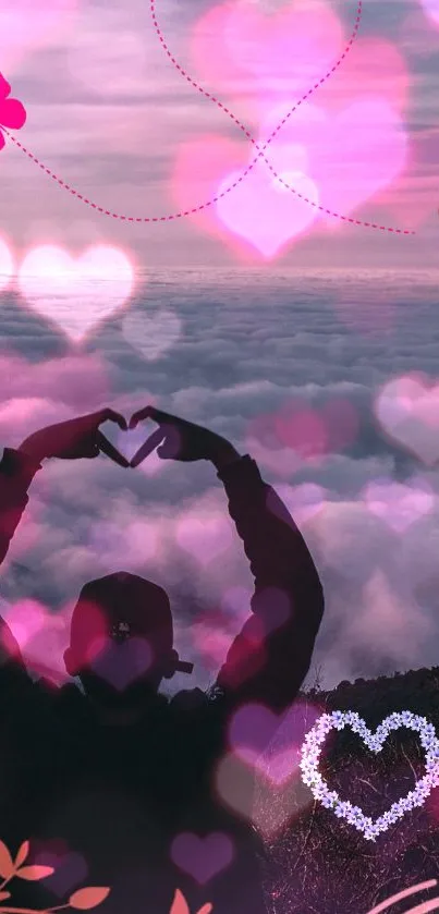 Silhouette with heart hands against pink cloud-filled sky.