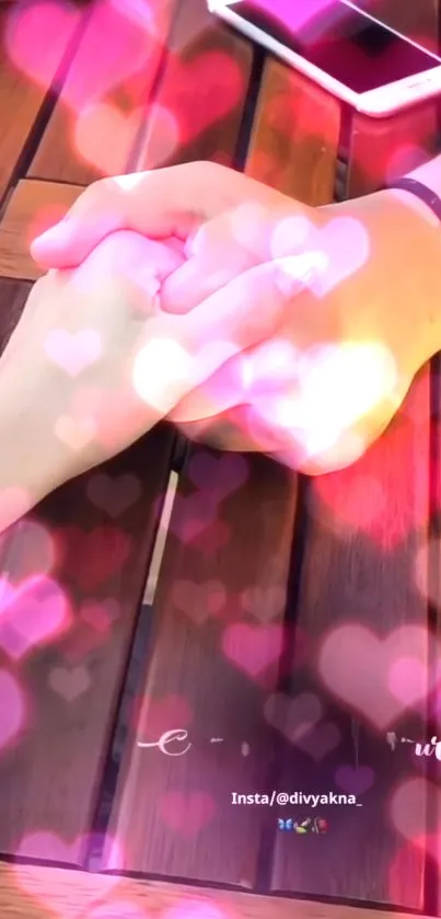 Two hands holding with heart-shaped lights on a wooden table.