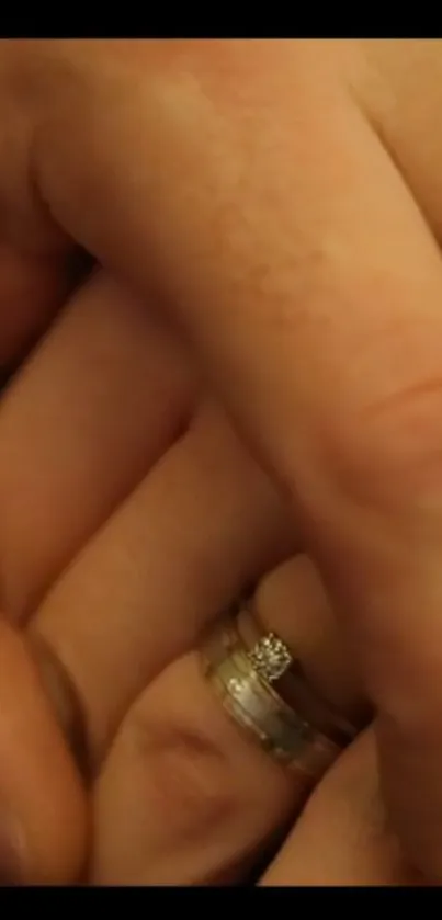 Romantic holding hands with rings on fingers, warm beige tones.