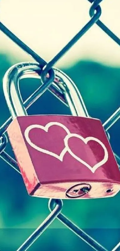 Red padlock with hearts on chain-link fence.