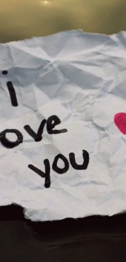 Crumpled note with 'I love you' and heart design.