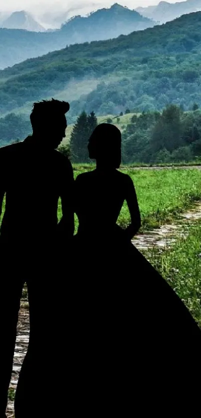 Silhouetted couple in front of a lush mountain landscape with a winding path.