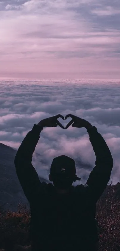 Silhouette forming heart at sunset over mountain background.