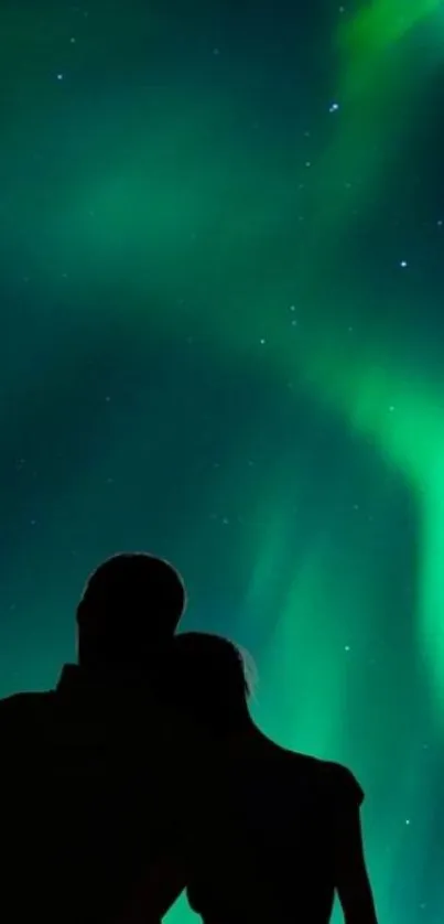 Silhouetted couple under the aurora borealis glow.