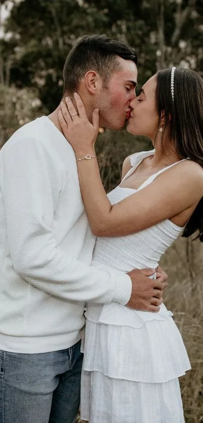 Couple sharing a romantic kiss in nature, dressed in white.