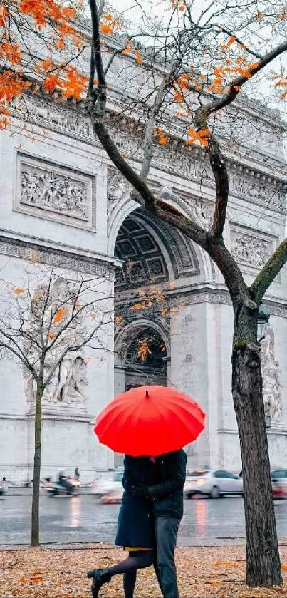 Couple in Paris with red umbrella and Arc de Triomphe in autumn.