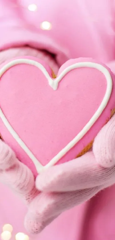 Hands holding a pink heart-shaped cookie with a soft glowing background.