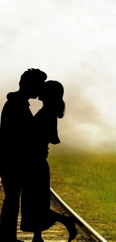 Silhouette of couple kissing on grassy railway with cloudy sky