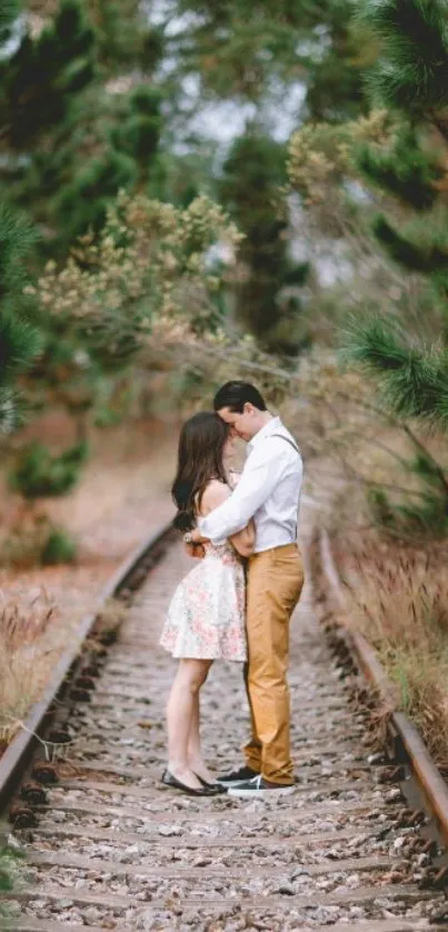 Couple embracing on railway track, surrounded by greenery.