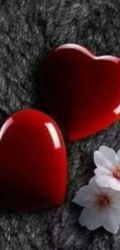 Two glossy red hearts with white flowers on a textured background.