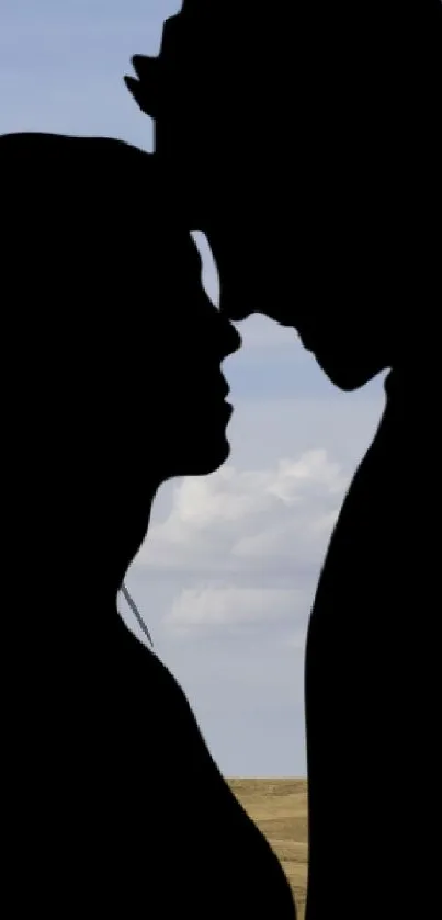 Silhouette of a couple against a blue sky with wind turbines.