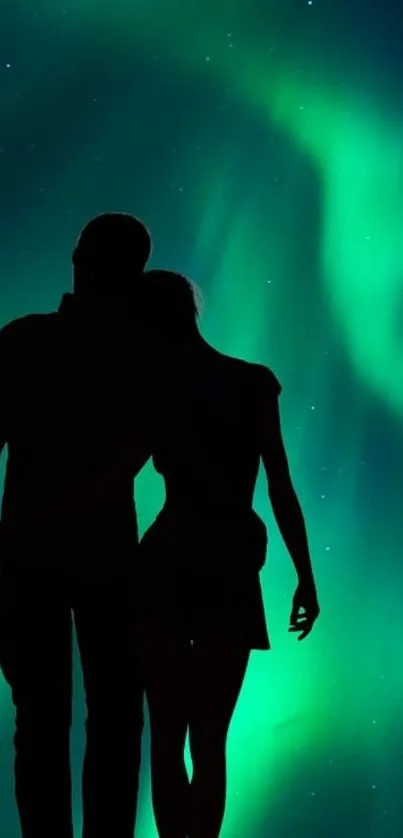 Silhouetted couple under vibrant aurora display.