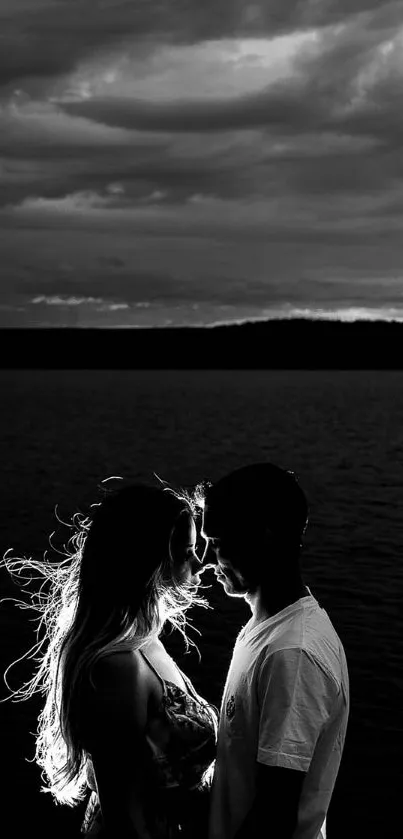 Romantic silhouette of a couple by a lake in black and white.